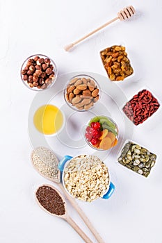 Bowl with ingredients for cooking  homemade granola on white background. Healthy snak.