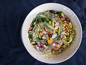 Bowl with ingredients for spring vegetables salad standing on wrinkly bluish cotton fabric