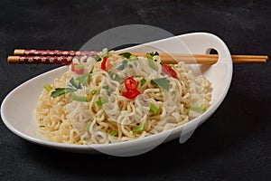 Bowl of instant noodles with chopsticks on black background