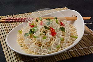 Bowl of instant noodles with chopsticks on black background