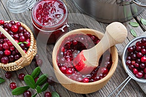 Bowl and jar of crushed cranberries, jam or sauce, basket of bog berries and strainer. Top view.