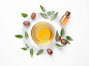 Bowl with jojoba oil and seeds on white background