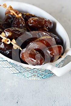 Bowl with juicy dates on a branch on a gray-blue background. Healthy tasty food.