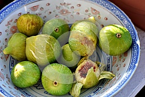 A bowl of juicy green figs and a slice of figs served in a bowl