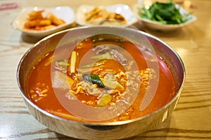 A bowl of kimchi ramen with side dishes in the background