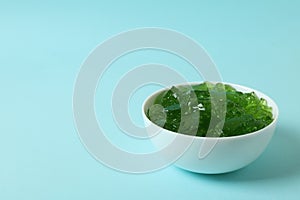 Bowl of kiwi jelly on blue background