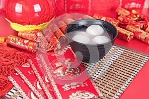 A bowl of Lantern Festival Lantern and festival red envelopes on the background covered with festive decorations. The Chinese char