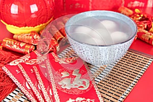 A bowl of Lantern Festival Lantern and festival red envelopes on the background covered with festive decorations. The Chinese char