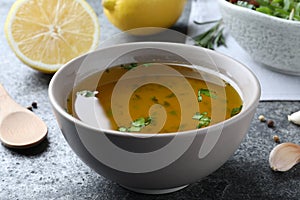 Bowl with lemon sauce on grey table, closeup. Delicious salad dressing