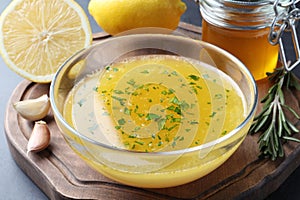 Bowl with lemon sauce and ingredients on table, closeup. Delicious salad dressing