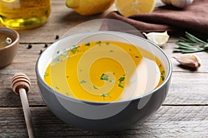 Bowl with lemon sauce on wooden table, closeup. Delicious salad dressing