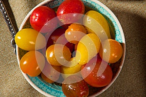 A bowl of little kind orange and red tomatoes.