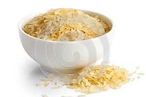 Bowl of long grain parboiled rice isolated on white. Spilled rice.