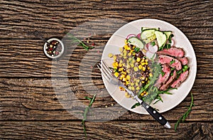 Bowl lunch with grilled beef steak and quinoa, corn, cucumber, radish and arugula