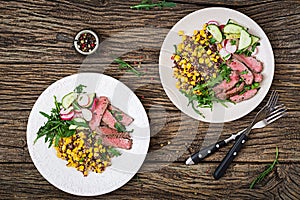 Bowl lunch with grilled beef steak and quinoa, corn, cucumber, radish and arugula