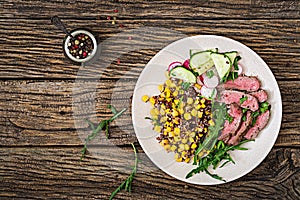 Bowl lunch with grilled beef steak and quinoa, corn, cucumber, radish and arugula