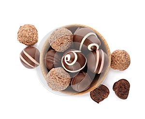 Bowl with many different delicious chocolate truffles on white background, top view