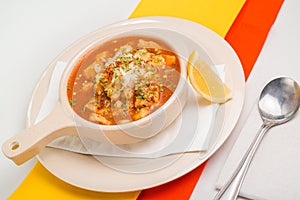 Bowl of menudo with spices and a slice of lime photo