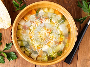 bowl of minestrone soup with toast on rustic wooden background, top view.