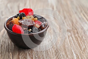 Bowl with mix of dried fruits and berries on wooden background