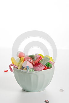 Bowl mixed colorful candy on withe background, kids holidays