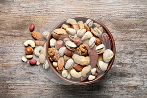 Bowl with mixed organic nuts on wooden background