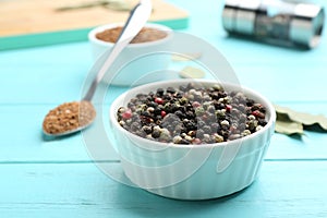 Bowl of mixed pepper corns on blue wooden table