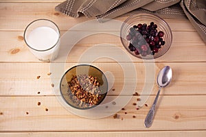 Bowl with muesli, frozen berries and glass of milk on wooden background