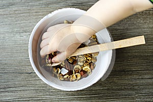 Bowl with muesli and spoon on the wooden table prepared for healthy breakfast, child hand