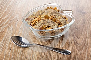 Bowl with muesli, teaspoon on wooden table