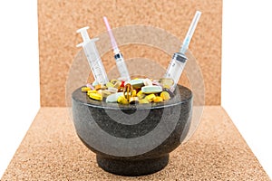 Bowl of pills and syringes addiction concept