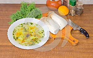 Bowl of mushroom soup and uncooked Eringi mushrooms beside