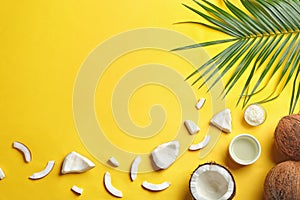 Bowl of natural organic oil and coconuts on yellow background, flat lay