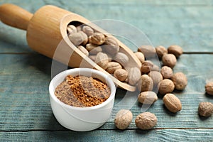 Bowl of nutmeg powder and scoop with seeds on light blue wooden table