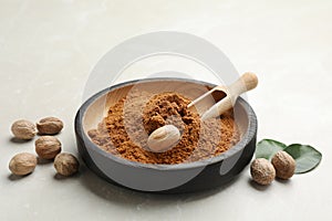 Bowl of nutmeg powder with seeds on white table