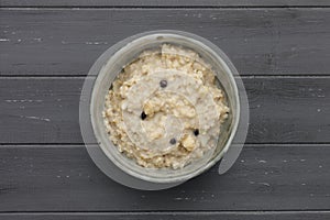 A bowl of nutritious blueberry and apple porridge shot from above on a dark wooden background