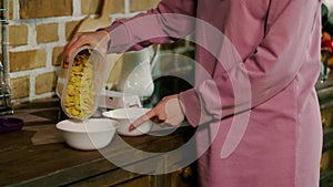 Bowl of oat breakfast cereal. The girl pours dry cereal into the bowl