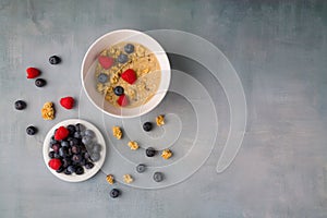 bowl of oat granola with yogurt, fresh raspberries, blueberries and nuts , healthy breakfast