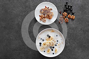 .Bowl of oatmeal porridge with banana and blueberry on vintage table top view in flat lay style