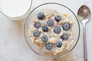 Bowl of oatmeal porridge with blueberry on marble table