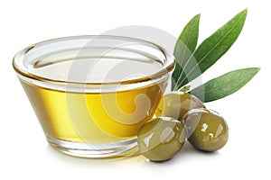 Bowl of olive oil and green olives with leaves