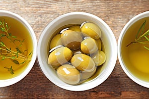 Bowl with olives in oil on table, top view