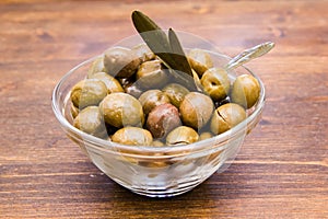 Bowl with olives and olive branch on wood