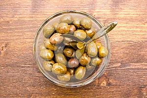 Bowl with olives and olive branch on wood from above