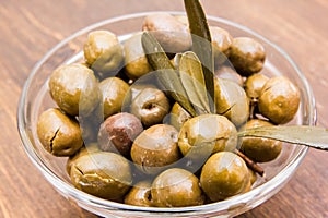 Bowl with olives and olive branch on wood close up