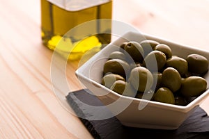 A bowl of olives with the olive oil bottle in the background