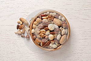 Bowl with organic mixed nuts on white wooden background
