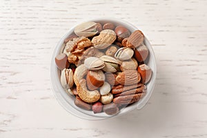 Bowl with organic mixed nuts on white wooden background