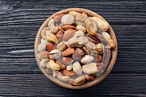 Bowl with organic mixed nuts on wooden background