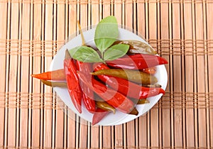 Bowl of pickled Red hot chili peppers on wooden background.